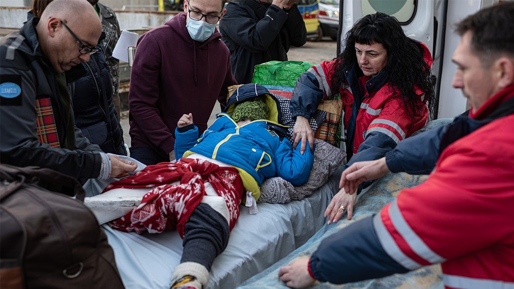 Medics move a boy from one stretcher to another before putting him in an ambulance car that would evacuate him to Poland on March 19, 2022 in Lviv, Ukraine. The evacuation programme removes sick children from the war in Ukraine and undertakes to match each child to a foreign hospital that has the capacity to continue their care. (Photo by Alexey Furman/Getty Images)