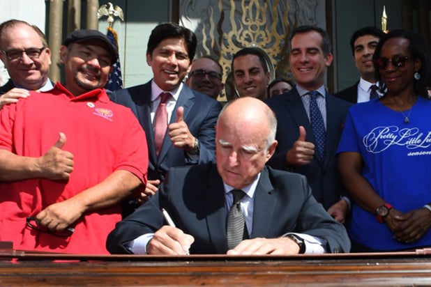 Caption:California Governor Jerry Brown, signs into law AB1839, the California Film and Television Job Retention Act, in front of TCL Chinese Theatre in Hollywood, California, September 18, 2014 while surrounded by state and local politicans and movie industry and union figures. The legislation increases Californias $100 million Film and TV Tax Credit Program to $330 million a year in an effort to keep entertainment production, and the jobs that go with, in California. AFP PHOTO / Robyn Beck (Photo credit should read ROBYN BECK/AFP/Getty Images)
