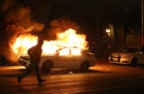 FERGUSON, MO - NOVEMBER 24: A police officer runs by a burning police car during a demonstration on November 24, 2014 in Ferguson, Missouri. A St. Louis County grand jury has decided to not indict Ferguson police Officer Darren Wilson in the shooting of Michael Brown that sparked riots in Ferguson, Missouri in August. (Photo by Justin Sullivan/Getty Images)