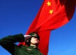 A Chinese flag waves behind a saluting soldier china