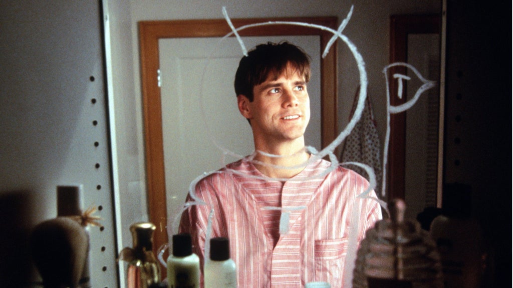 A person stands in front of a mirror with various toiletries on the countertop. They are wearing a red and white striped shirt with a white paper collar and cuffs attached. White lines are drawn on the mirror behind them, resembling a door frame.