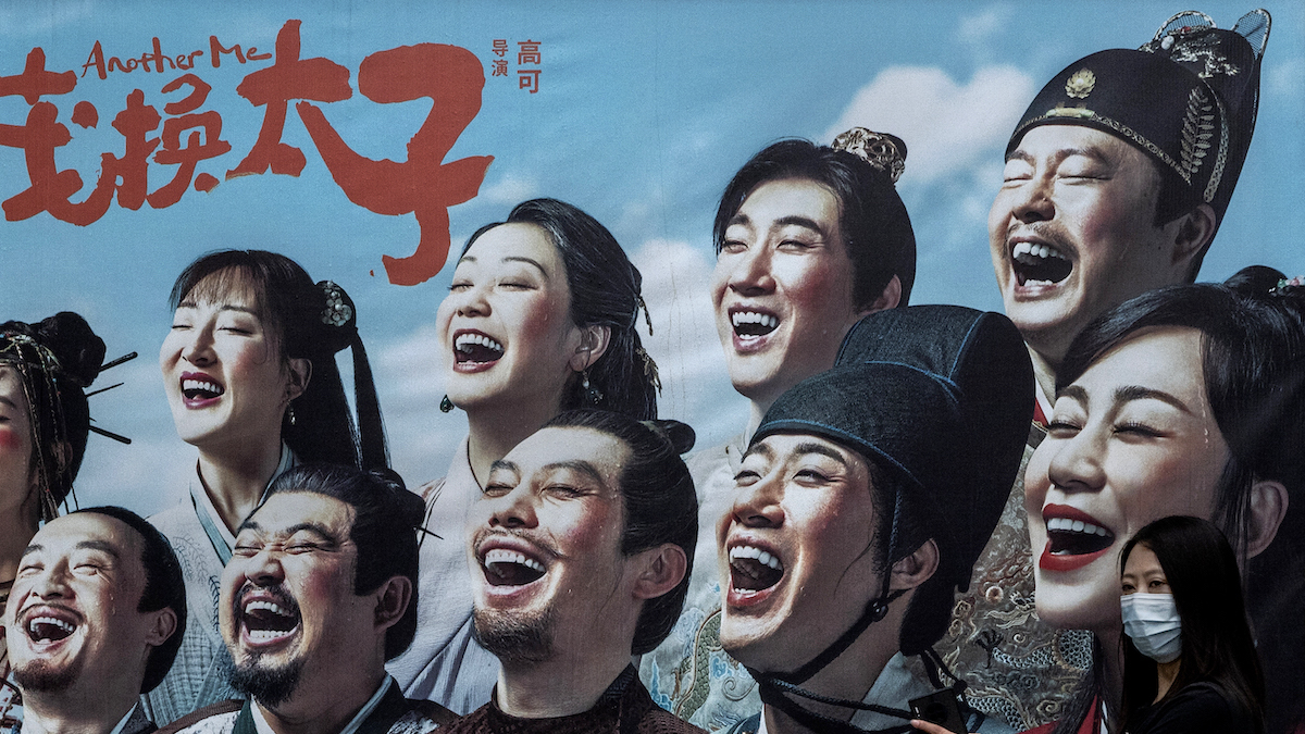 A woman walks past a billboard for the 2022 Chinese movie "Another Me" in Beijing.