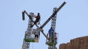Workers dismantle an "X" sign on top of the headquarters of X Corp., formerly known as Twitter, in San Francisco.