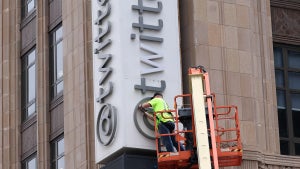 A worker removes letters from the Twitter sign that is posted on the exterior of Twitter headquarters (Photo Credit: Getty Collection)
