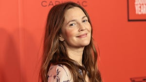 A light-skinned woman with long light brown/auburn hair in front of an orange background.