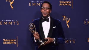 A Black man in a tux holds a trophy
