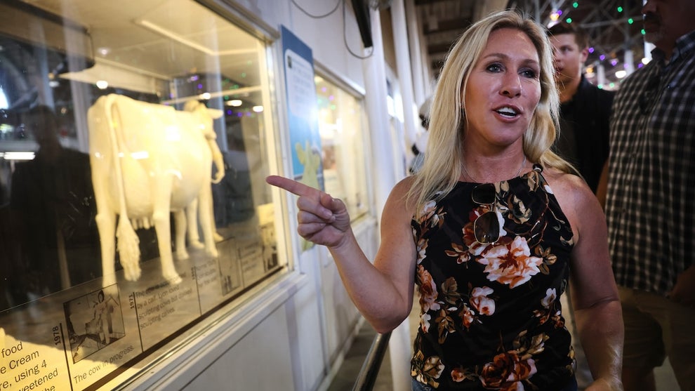 A woman points to a butter cow in a window