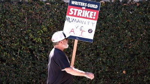 A WGA picketer's sign reads "Humanity vs. AI" outside Warner Bros. Studio on Aug. 16.