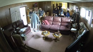 A woman points to her door, directing police to leave