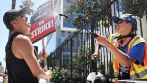 Strike captain uses a mister and fan to cool off strikers in the summer heat in Los Angeles.