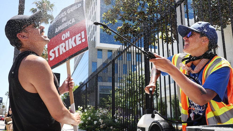 Strike captain uses a mister and fan to cool off strikers in the summer heat in Los Angeles.