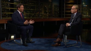 Two men sit in chairs across from one another