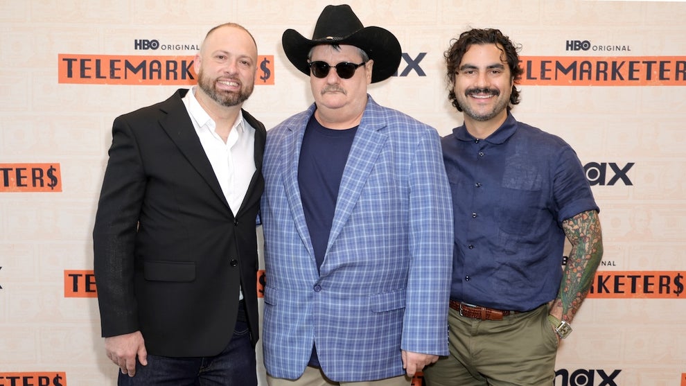 Three men stand in front of a background that reads "HBO Telemarketers." The two on the left have light-toned skin, while the one on the right has medium-toned skin. The two on the left wear blazers. The one in the center wears a cowboy hat and dark sunglasses.