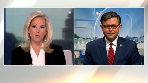 Two people with light-toned skin appear in a TV split screen, with images of Washington D.C. behind them.