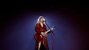 Taylor Swift on stage in a long red sparkly cloak