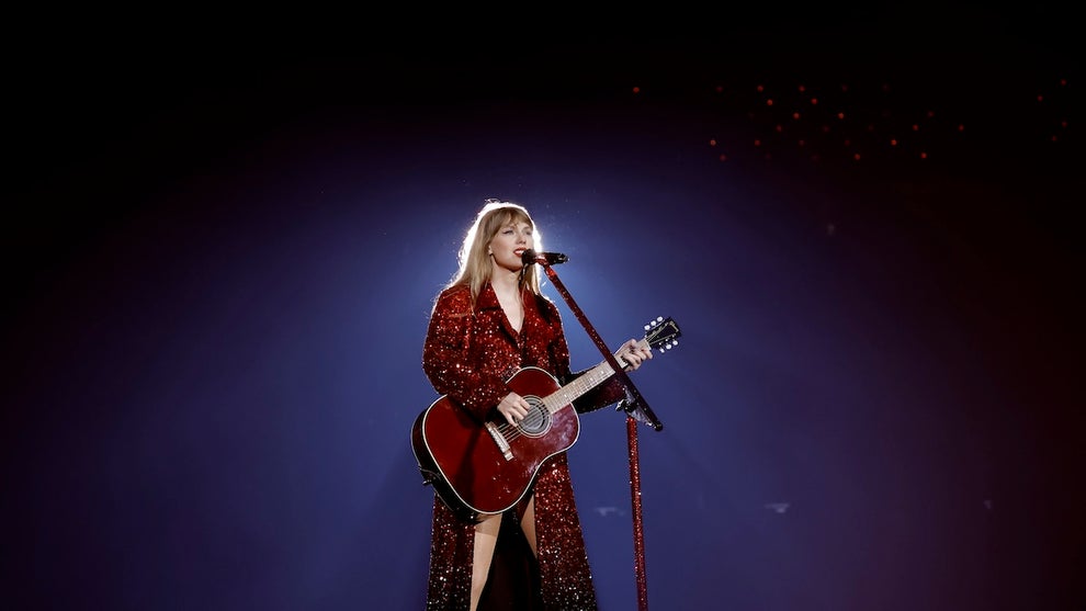 Taylor Swift on stage in a long red sparkly cloak