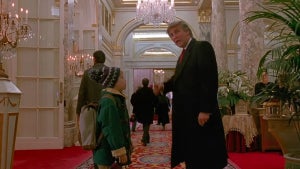 A tall man points down a hallway in a fancy hotel, speaking with a small child.