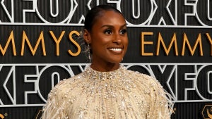 A Black woman smiles in front of a bcakdrop for the Emmys
