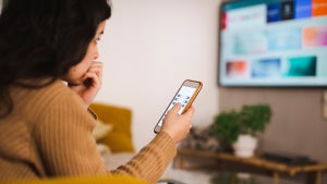Woman looking at her phone while she watches TV