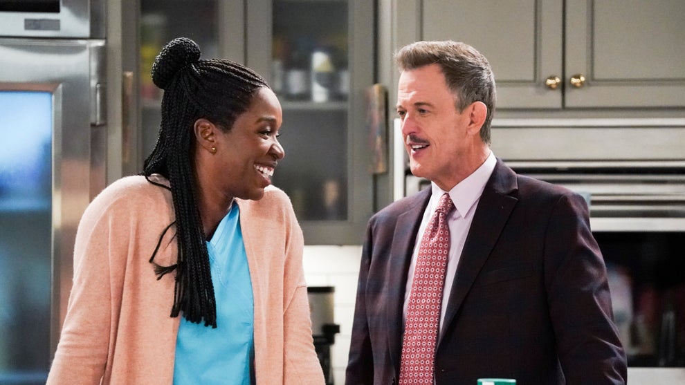 A couple laughs and smiles at each other in their kitchen