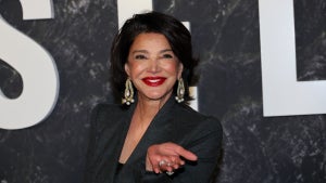 Shohreh Aghdashloo walks down the "Damsel" red carpet, smiling and gesturing toward the camera