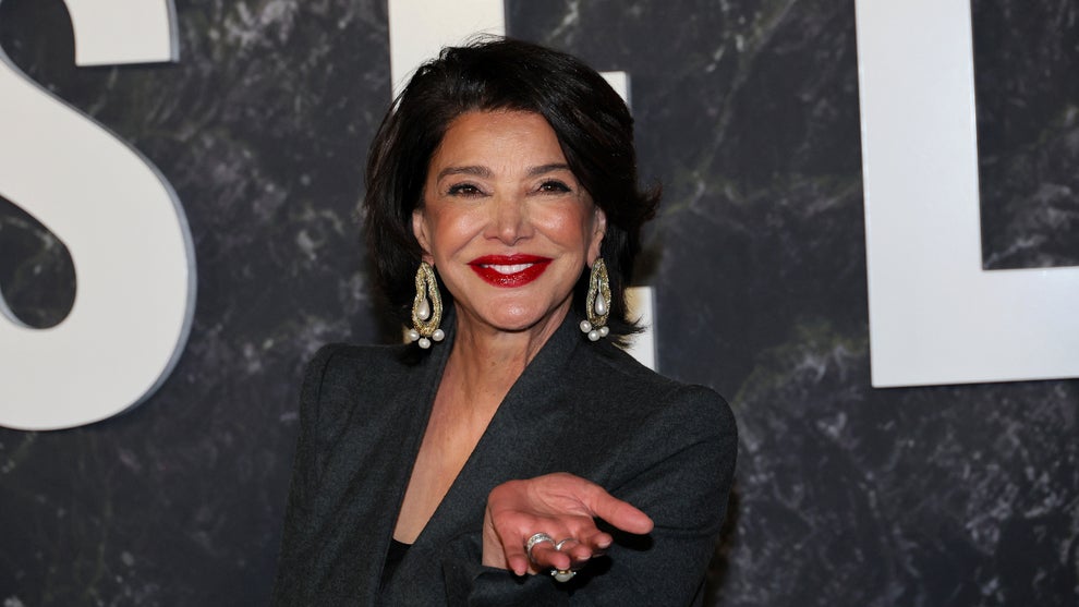 Shohreh Aghdashloo walks down the "Damsel" red carpet, smiling and gesturing toward the camera