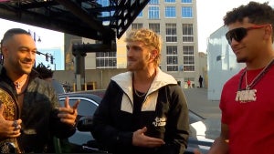 Men with medium-toned skin on either side, a man with light-toned skin in the middle, standing outside in a parking lot next to a black car. The men are Damian Priest, Logan Paul and Patrick Mahomes.