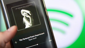 A closeup of Taylor Swift's "Tortured Poets Department" album cover as seen on a phone playing her music, with a Spotify logo in the background.