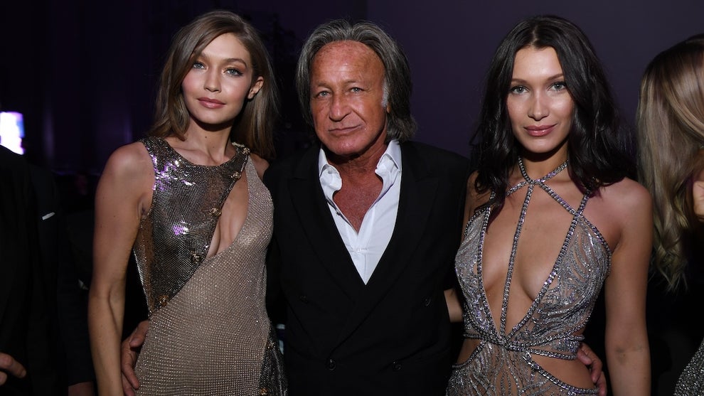 A woman with sandy blond hair on the left, an older man in the middle in a suit, and a woman with black hair on the right. They all have medium-toned skin. The women are both wearing dresses.