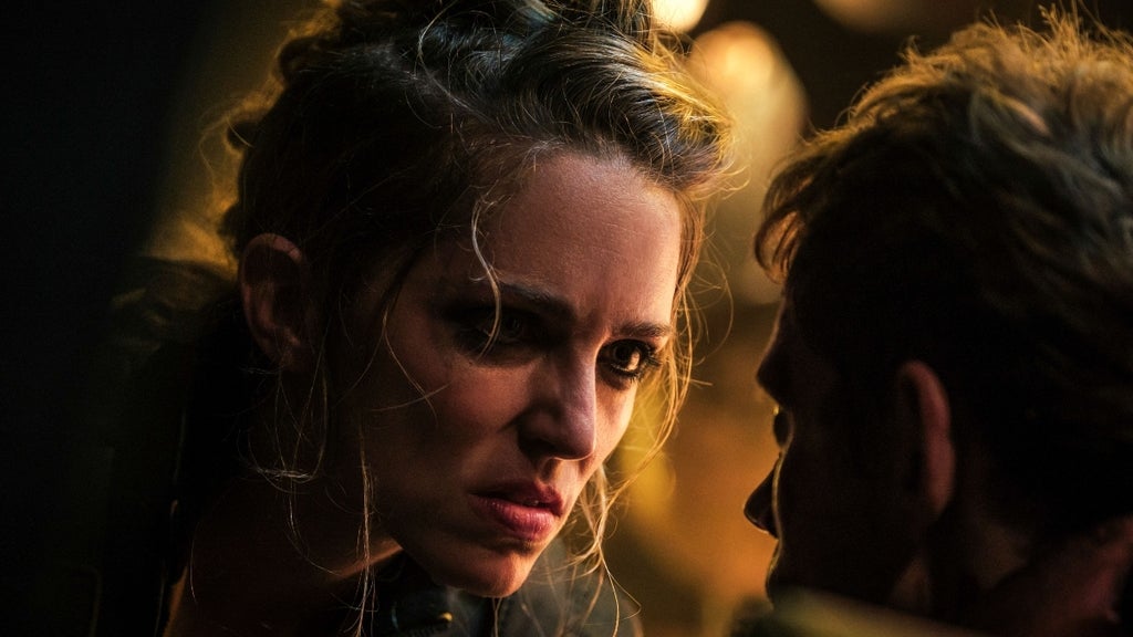 A woman with unkempt hair leans into someone's face and gives him a hard stare