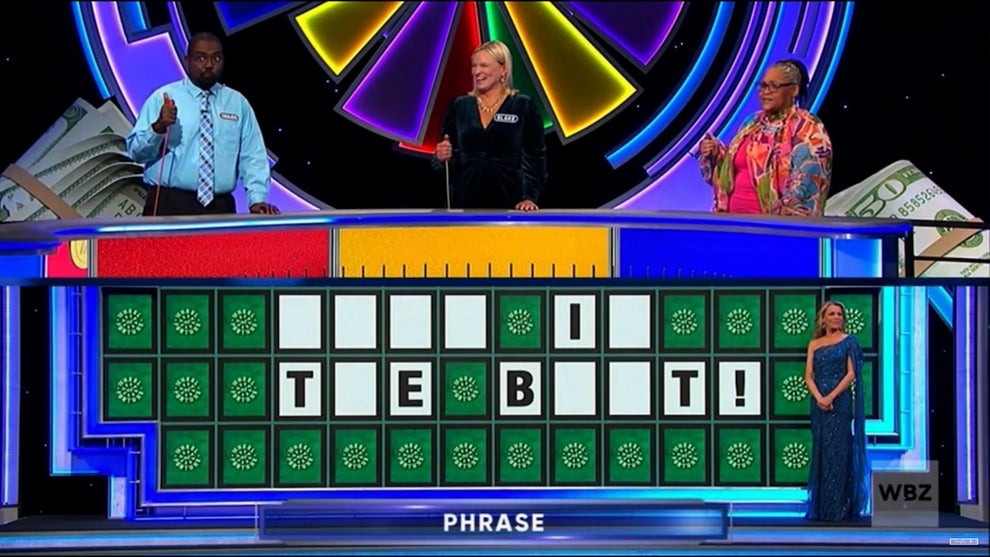 Wheel of Fortune contestants play the game as the board shows the unsolved puzzle "____ I_ T_E B__T!"