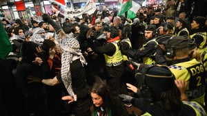 A group of protesters interact with police in large numbers outside.