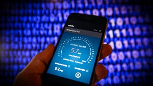 A photo of an internet speed test from Xfinity, with a hand holding a phone and 1's and 0's in the background.