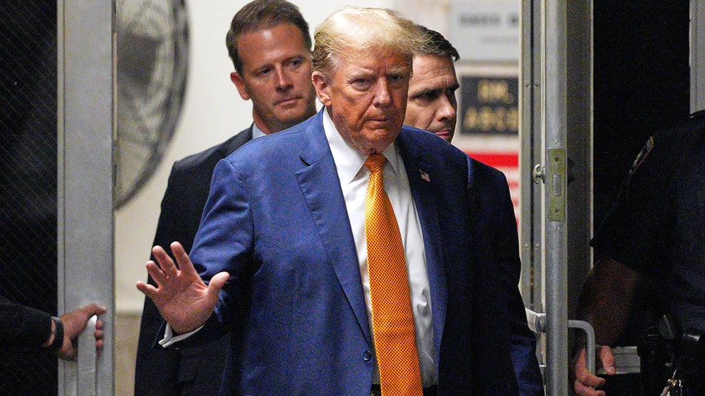 Donald Trump wearing a blue suit and yellow tie arriving in court
