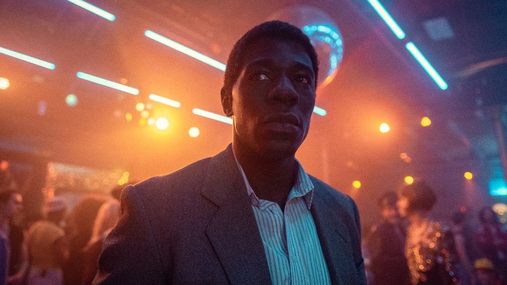 A man in a suit gives a stern look in a brightly lit club