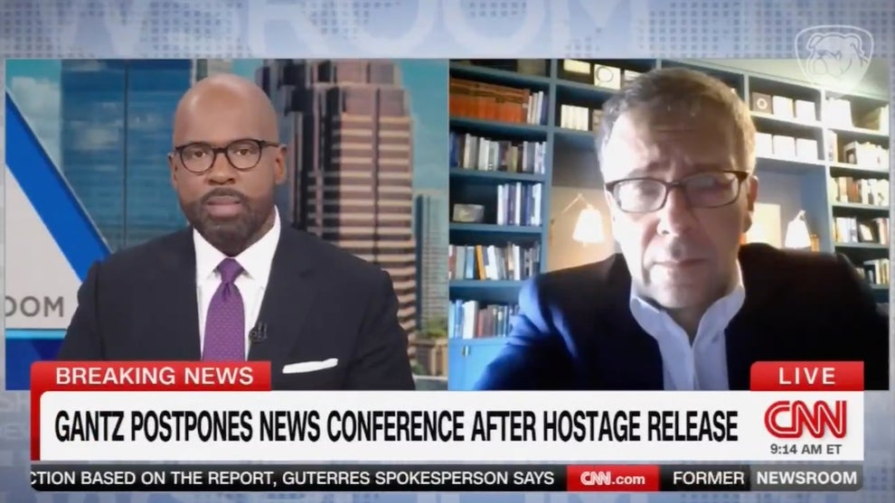 A chyron on the bottom of the screen reads "Gantz postpones news conference after hostage release." A Black man and a white man are shown in a split screen above, both wearing suits.