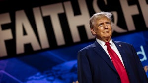 Donald Trump in front of a large banner reading "FAITH & FREEDOM."