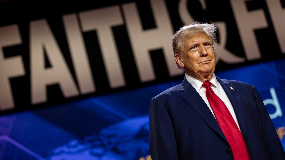 Donald Trump in front of a large banner reading "FAITH & FREEDOM."