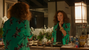 An older woman touches her face as she looks in a mirror.