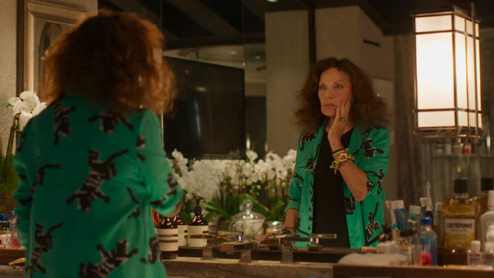 An older woman touches her face as she looks in a mirror.