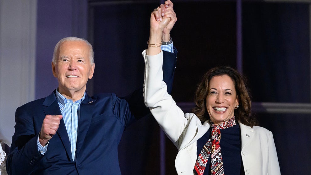 US President Joe Biden (L) and US Vice President Kamala Harris hold hands and gesture as they watch the Independence Day fireworks display from the Truman Balcony of the White House in Washington, DC, on July 4, 2024.