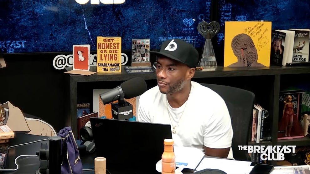A Black man sits in a studio in front of a computer monitor.