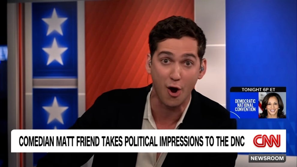 A man with light-toned skin makes an animated facial expression on a cable news set.