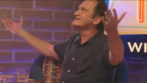 A man looks up and spreads his arms. He has light-toned skin as he sits back into a sofa.