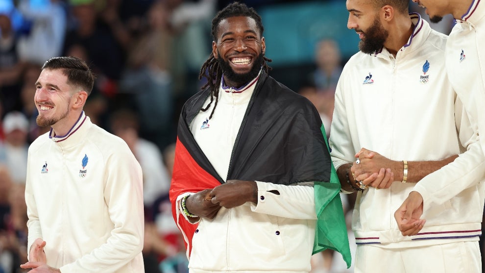 Silver medalist Mathias Lessort #26 of Team France smiles while wearing the flag of Martinique on the podium during the Men's basketball medal ceremony on day fifteen of the Olympic Games Paris 2024 at Bercy Arena on August 10, 2024 in Paris, France
