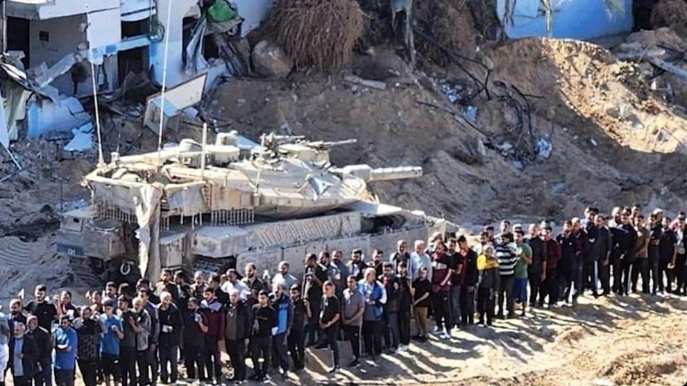 An image showing a line of men with a tank behind them.