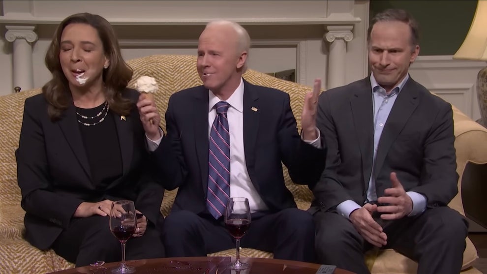 Three people sit on a couch, including one woman with dark-toned skin and two men with light-toned skin.