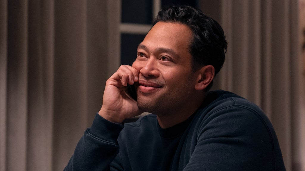 A man smiles while talking on a cell phone