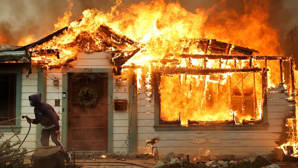 An Eaton resident resorts to using a garden hose to combat the encroaching fire. (Credit: Mario Tama/Getty Images)