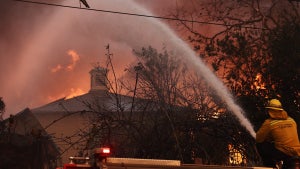 A firefighter sprays water as a home burns during the Eaton Fire. (Credit: Mario Tama/Getty Images)